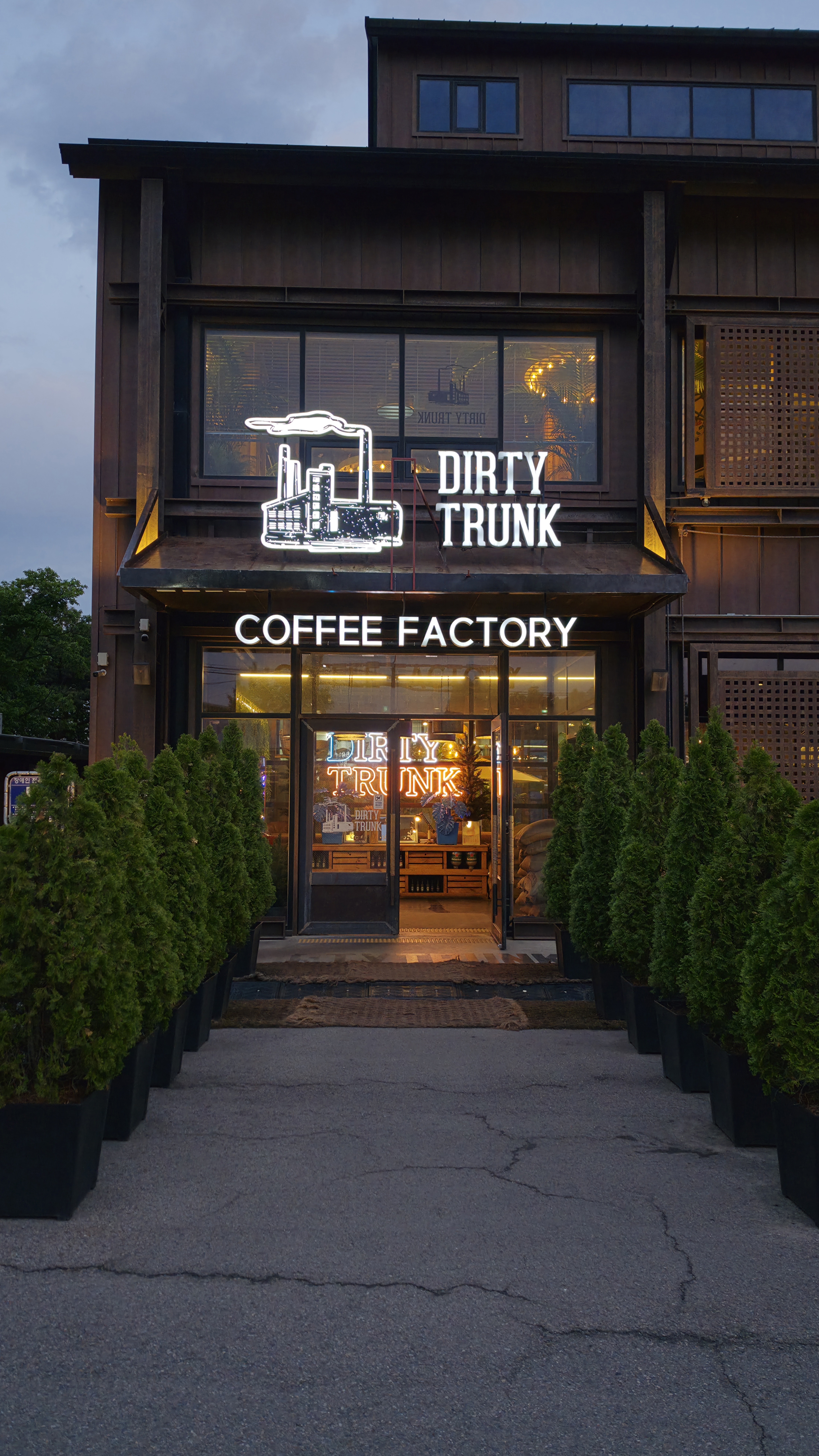 Lối vào ngoài Dirty Trunk với biển COFFEE FACTORY và cây ven đường